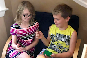 School Age Program - Girl and Boy playing Rock Paper Scissors on Couch