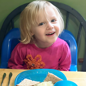 Child Care Wellness Policies - Girl Smiling at Lunch Table