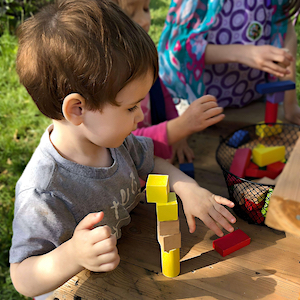Daily Learning Activities - Boy Stacking Blocks Outside