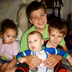 School Age Boy holding Infant Brother with Children on Both Sides of Him