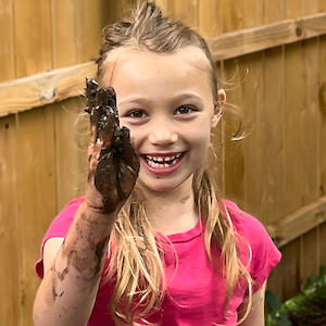 Messy Play - Smiling girl with muddy hands